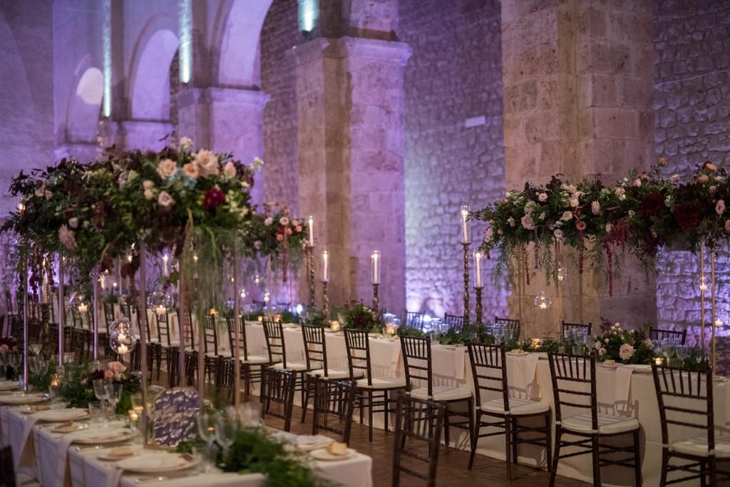 Un lungo tavolo con sopra tante candele e fiori.