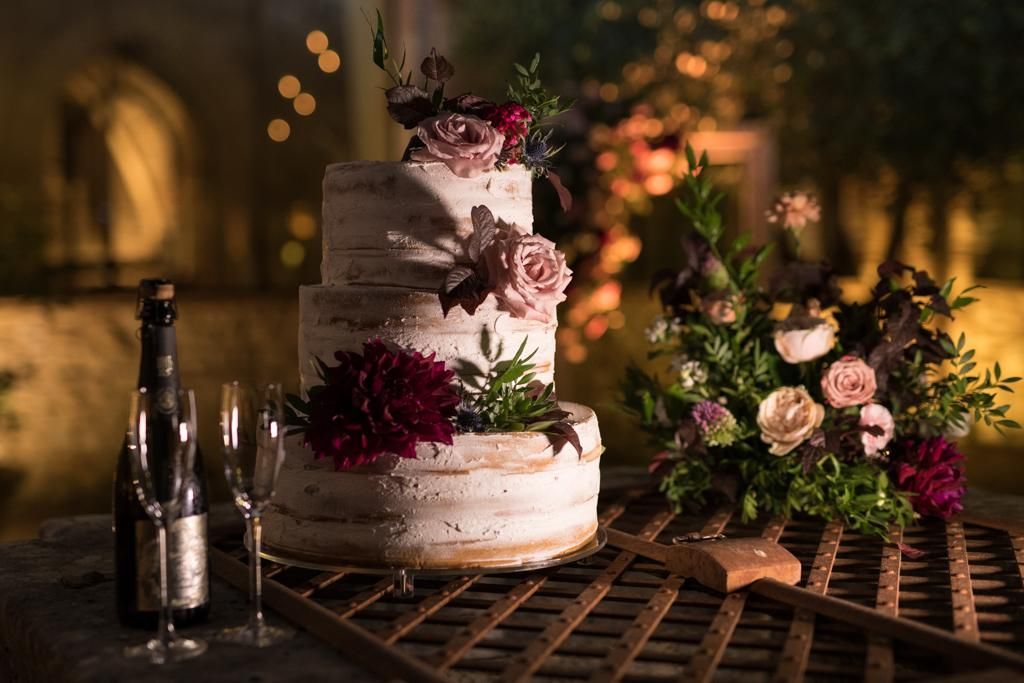 Una torta nuziale è seduta sopra un tavolo di legno.