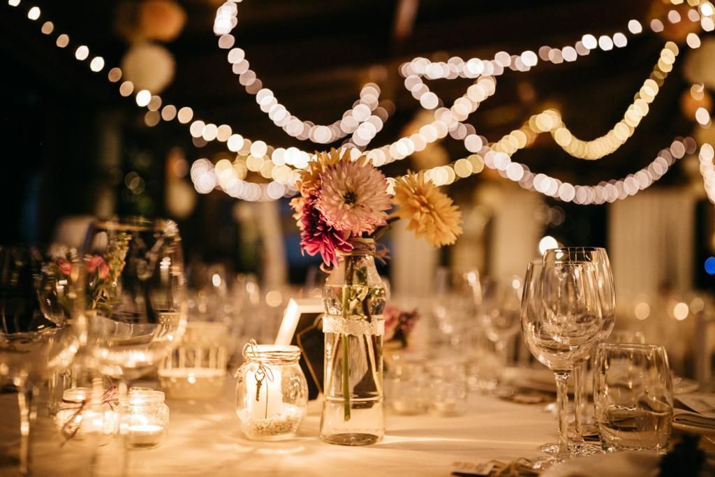 Una tavola apparecchiata per un ricevimento di nozze con sopra un vaso di fiori.