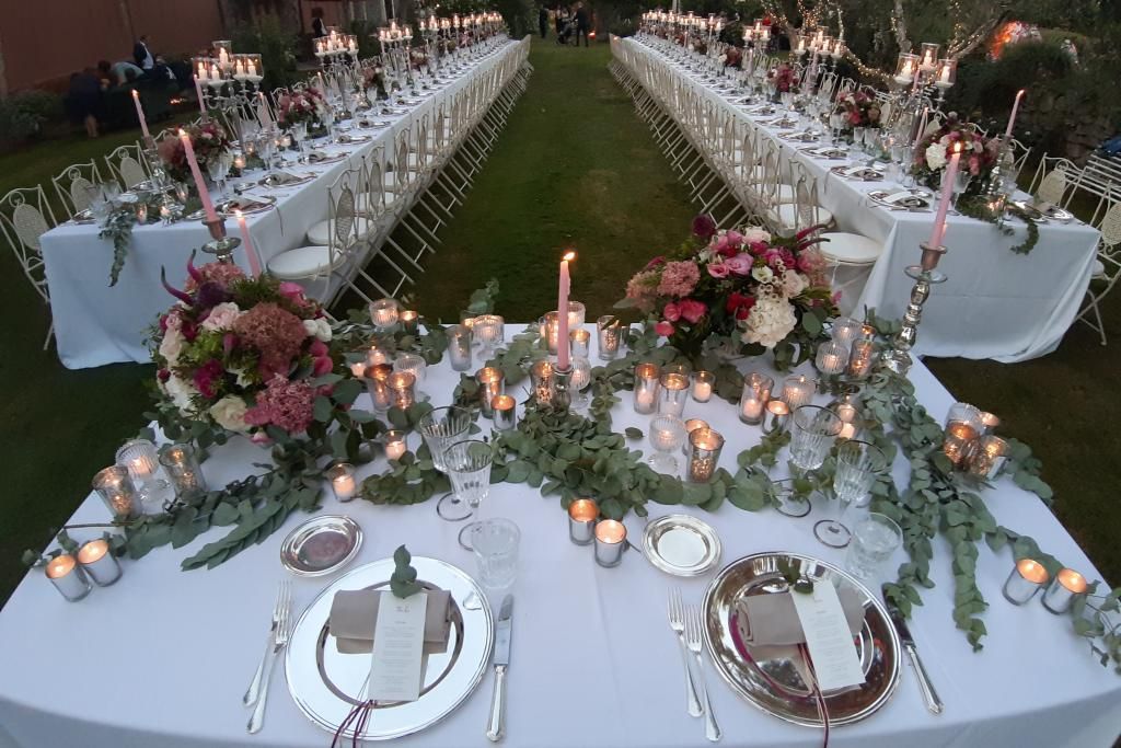 Un lungo tavolo con sopra candele e fiori