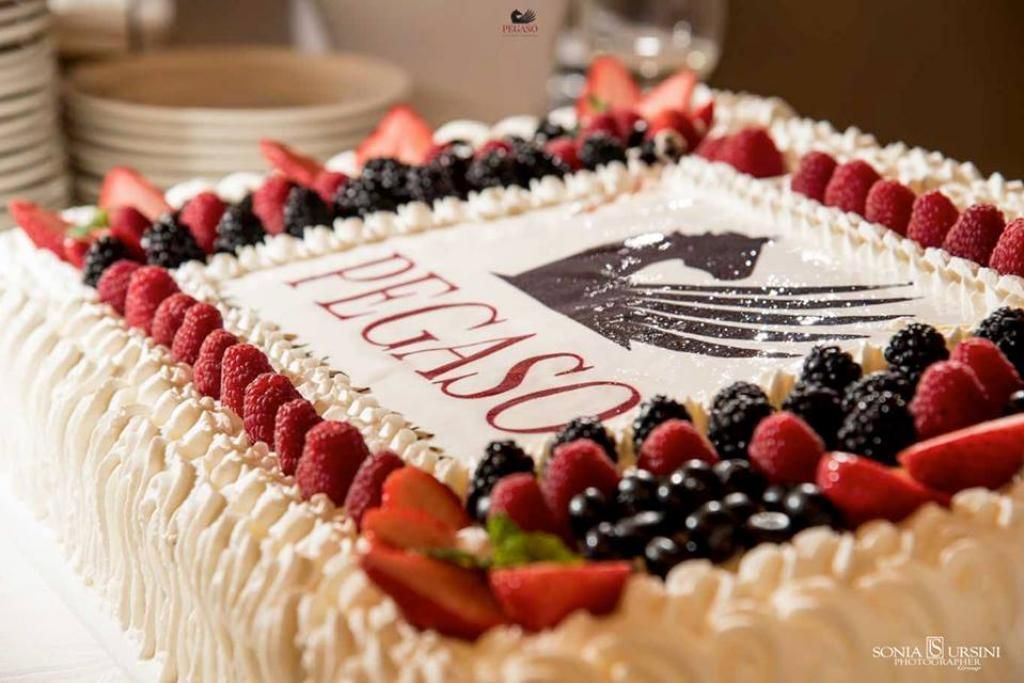 Una grande torta con sopra frutti di bosco e panna montata