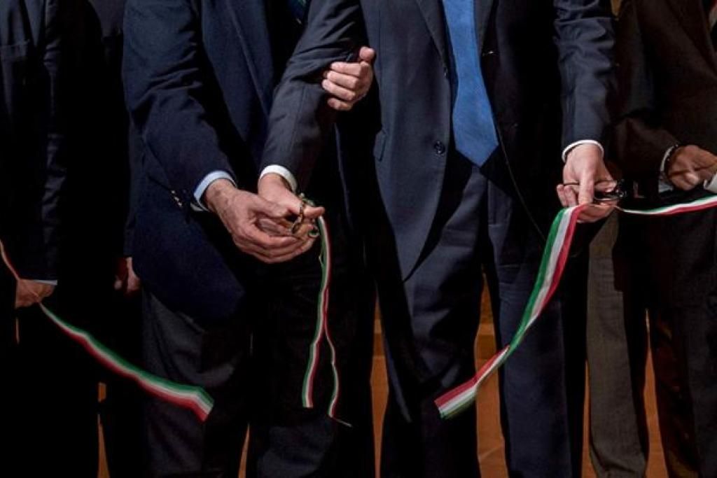 Un gruppo di uomini in giacca e cravatta sta tagliando un nastro