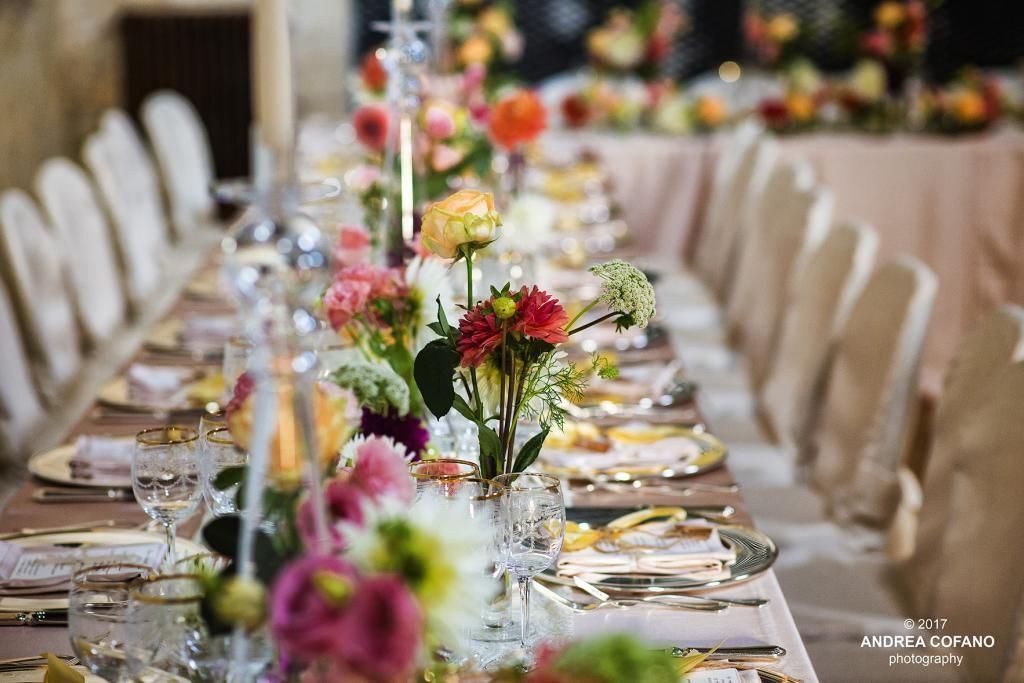 Un lungo tavolo con fiori e candele sopra.