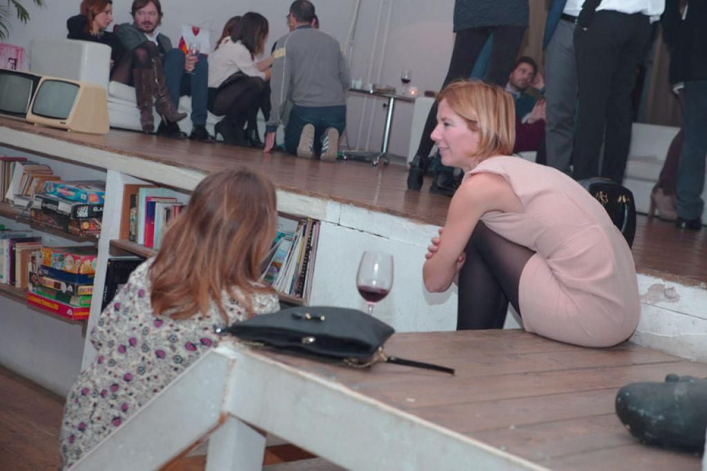 Una donna vestita di rosa è seduta a un tavolo con un bicchiere di vino.