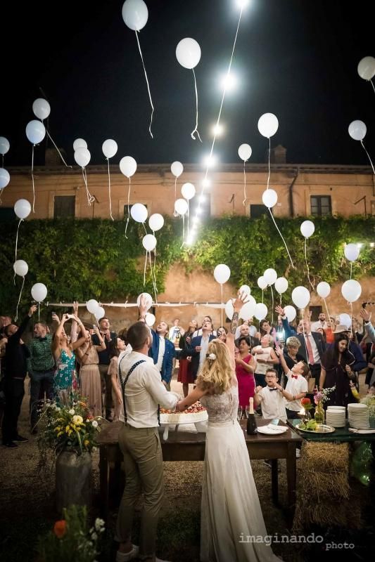 Gli sposi tagliano la torta nuziale mentre vengono lanciati in aria dei palloncini.