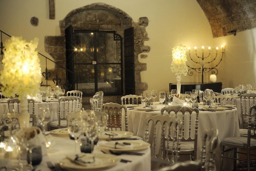 Una sala con tavoli e sedie allestita per un ricevimento di nozze