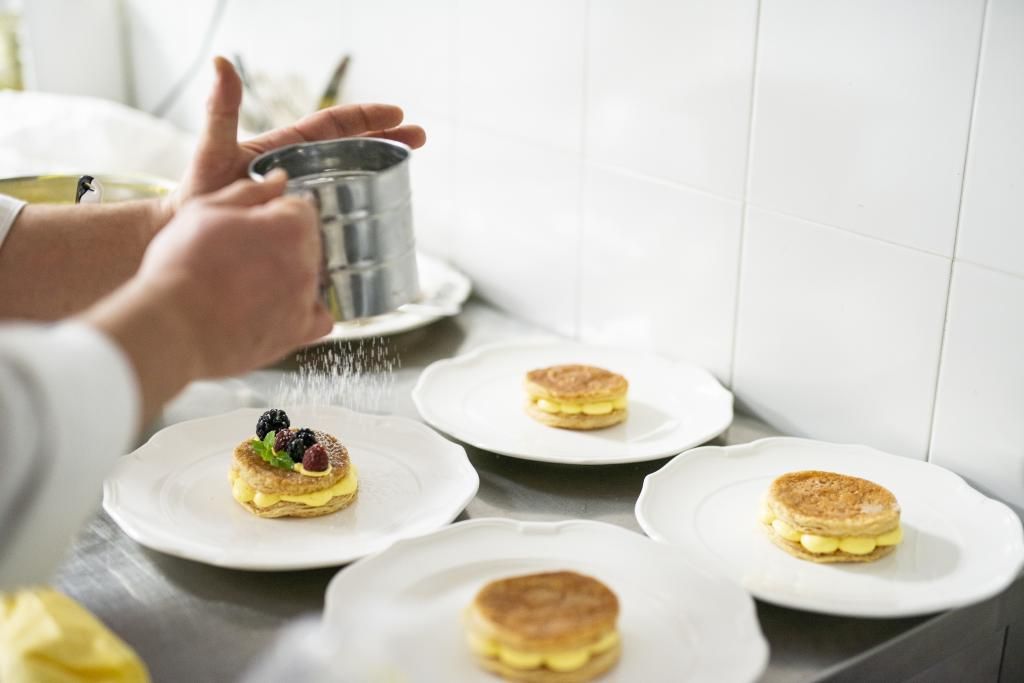 Una persona sta decorando un dessert con frutti di bosco su un piatto.