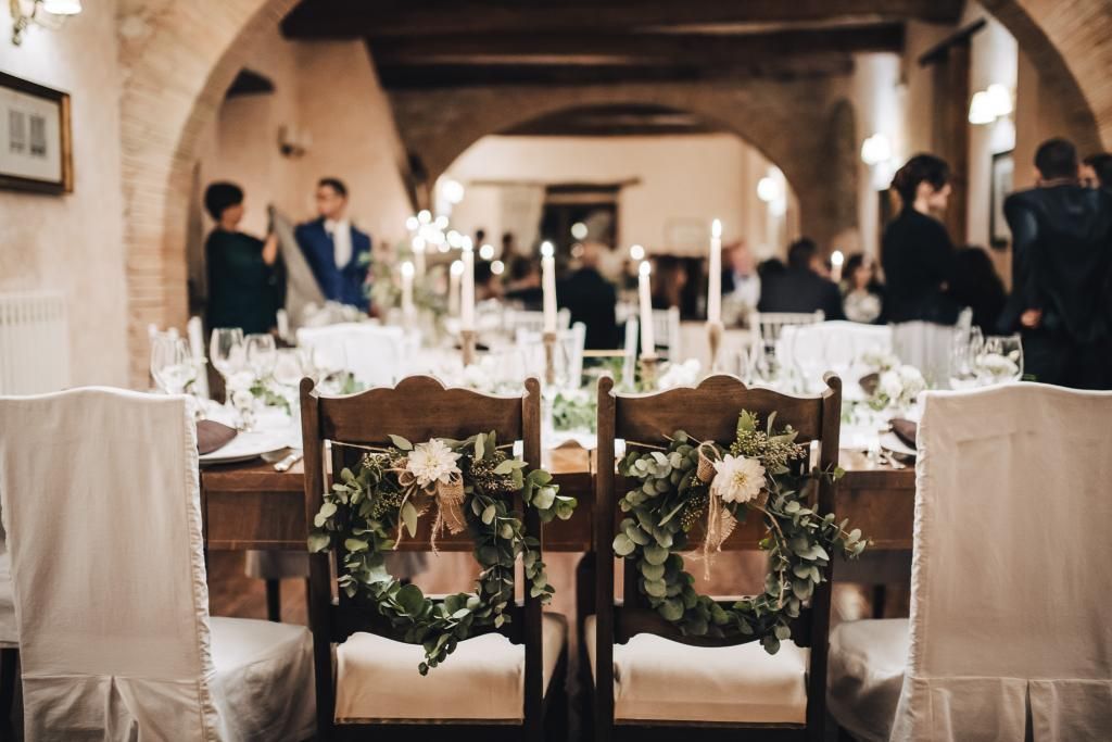 Le sedie degli sposi sono decorate con fiori e ghirlande.