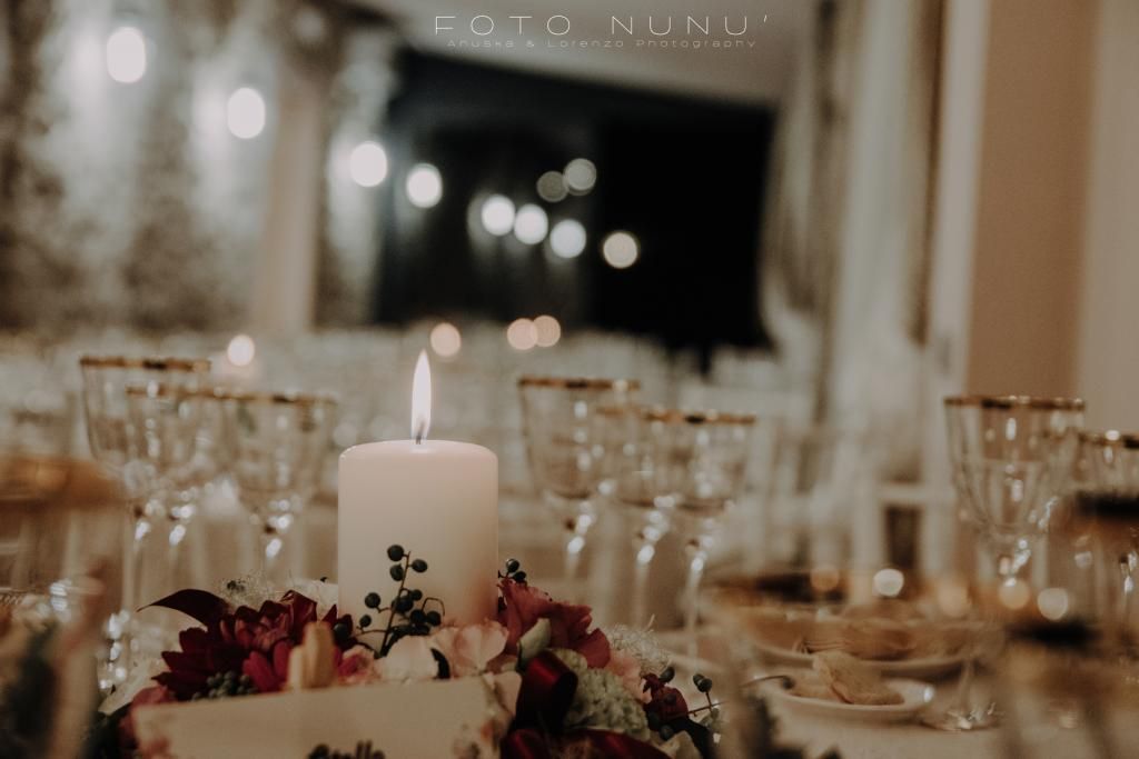 Una tavola apparecchiata per un ricevimento di nozze con una candela e fiori sopra.