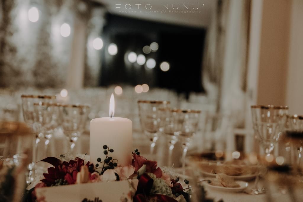 Una tavola apparecchiata per un ricevimento di nozze con una candela e fiori sopra.