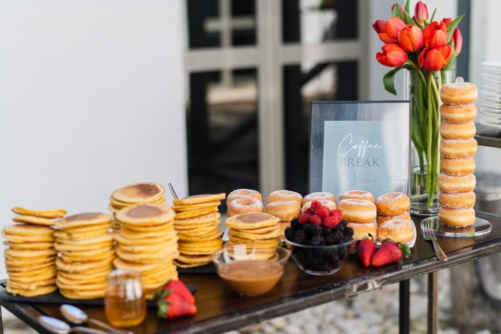 Un tavolo ricoperto di frittelle, ciambelle e frutti di bosco.