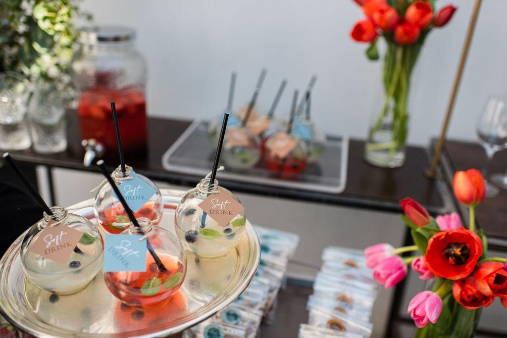 Un tavolo con sopra un vassoio di bevande e fiori.