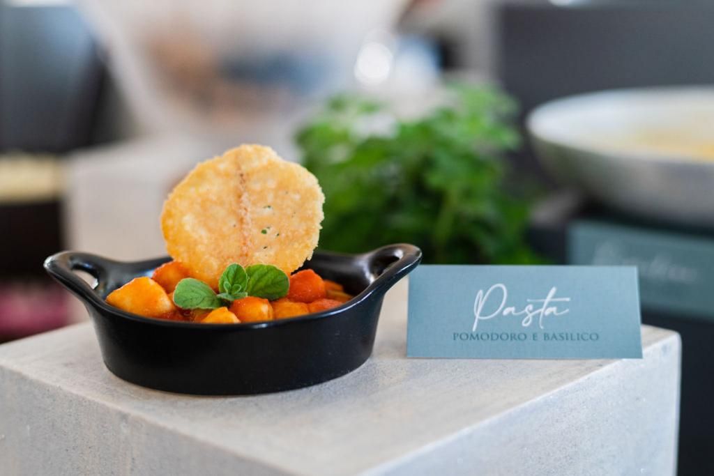 Una ciotola di cibo è seduta su un tavolo accanto a un cartello.