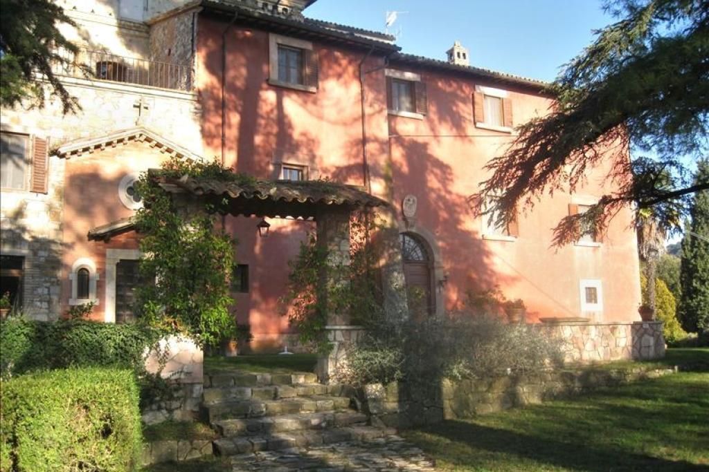 Una grande casa rossa è circondata da alberi e cespugli