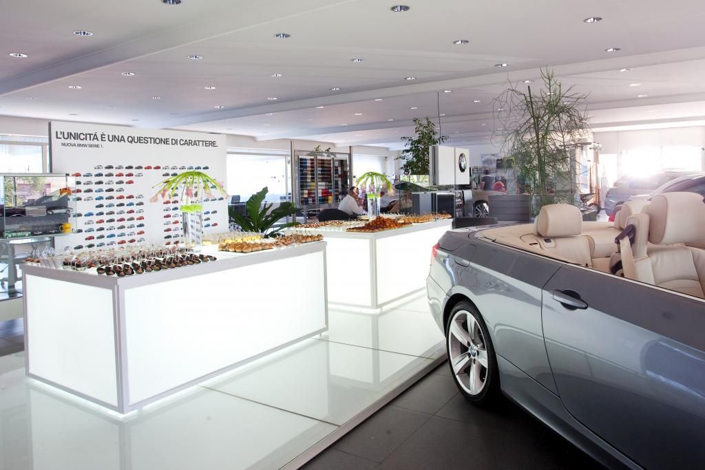 Un'auto è parcheggiata in uno showroom accanto a un tavolo con del cibo sopra.