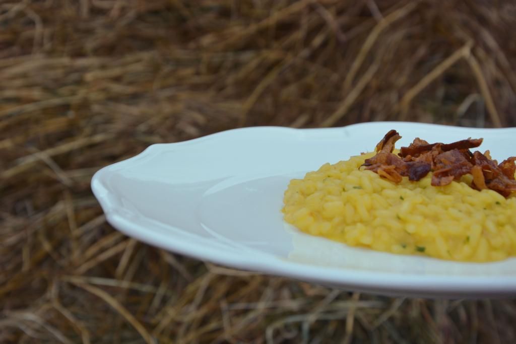 Un piatto bianco condito con riso giallo e pancetta