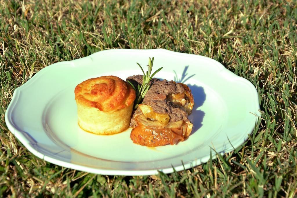 Un piatto bianco con sopra un pezzo di carne e una pasta frolla
