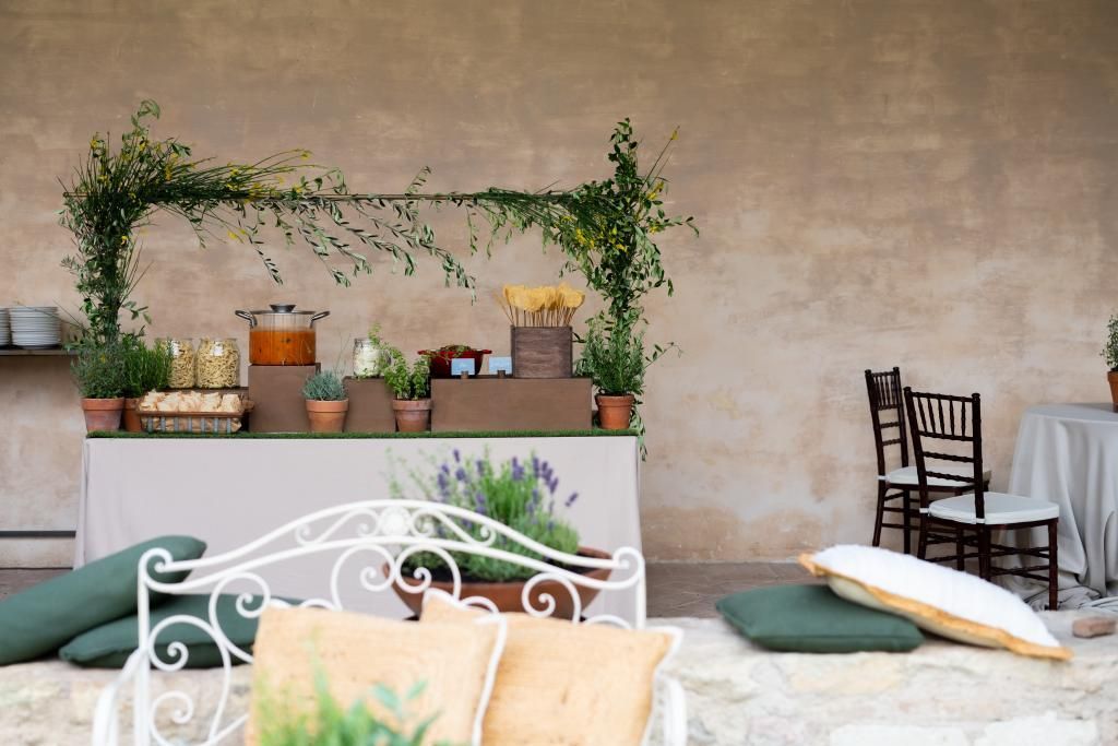 Davanti a un tavolo e sedie è seduta una panca bianca con dei cuscini sopra.