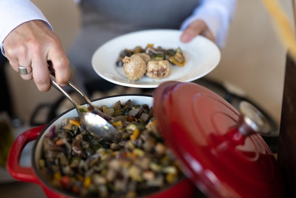 Una persona prende un piatto di cibo da una pentola rossa
