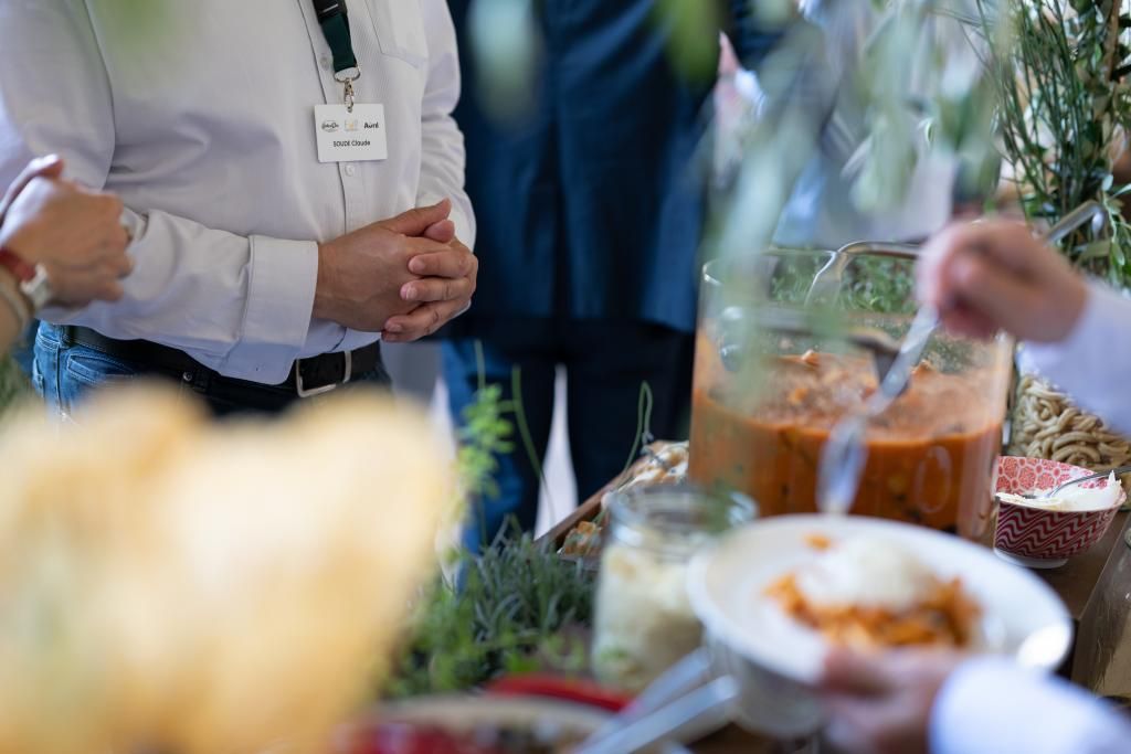 Un gruppo di persone è in piedi attorno a un tavolo e mangia del cibo.