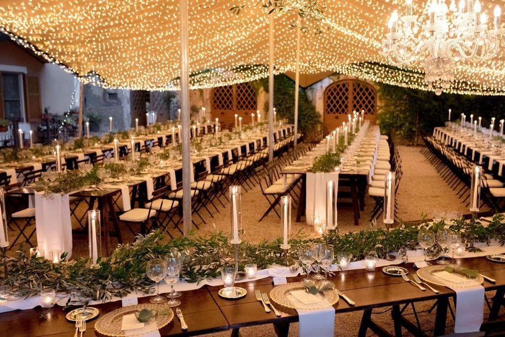 Ci sono molti tavoli e sedie allestiti per un ricevimento di nozze.