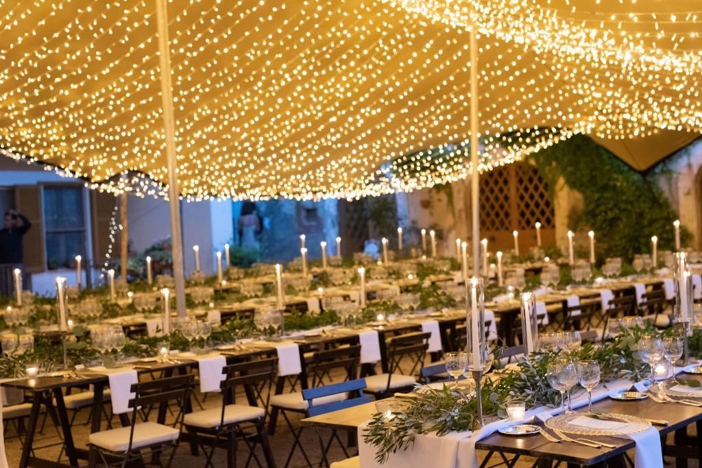 Una fila di tavoli e sedie sotto una tenda con luci.