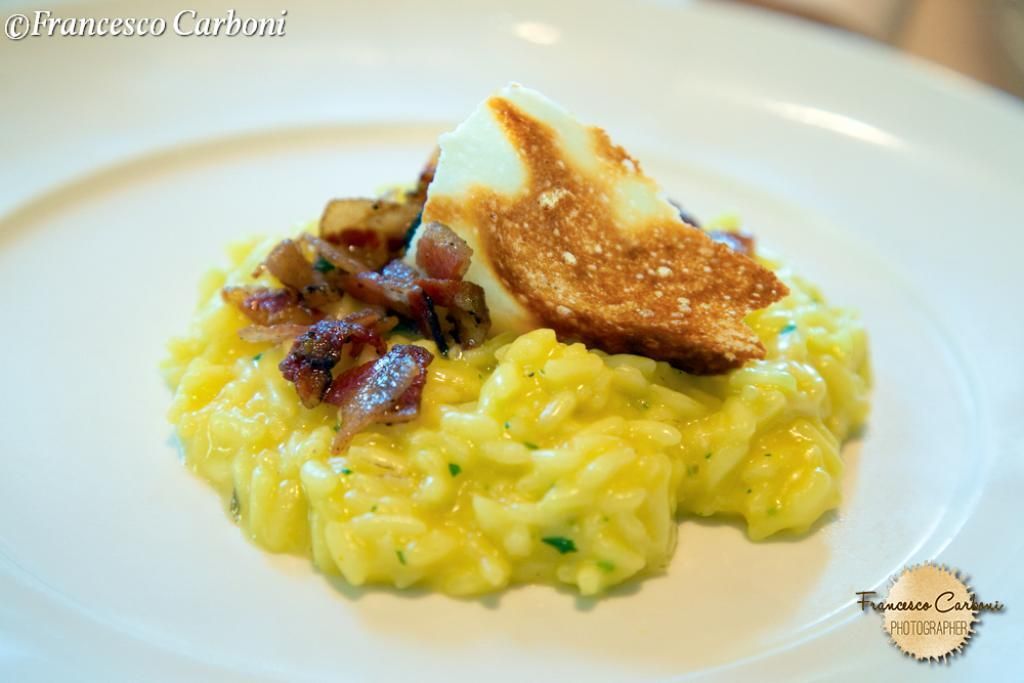 Un piatto bianco condito con riso giallo e un pezzo di formaggio