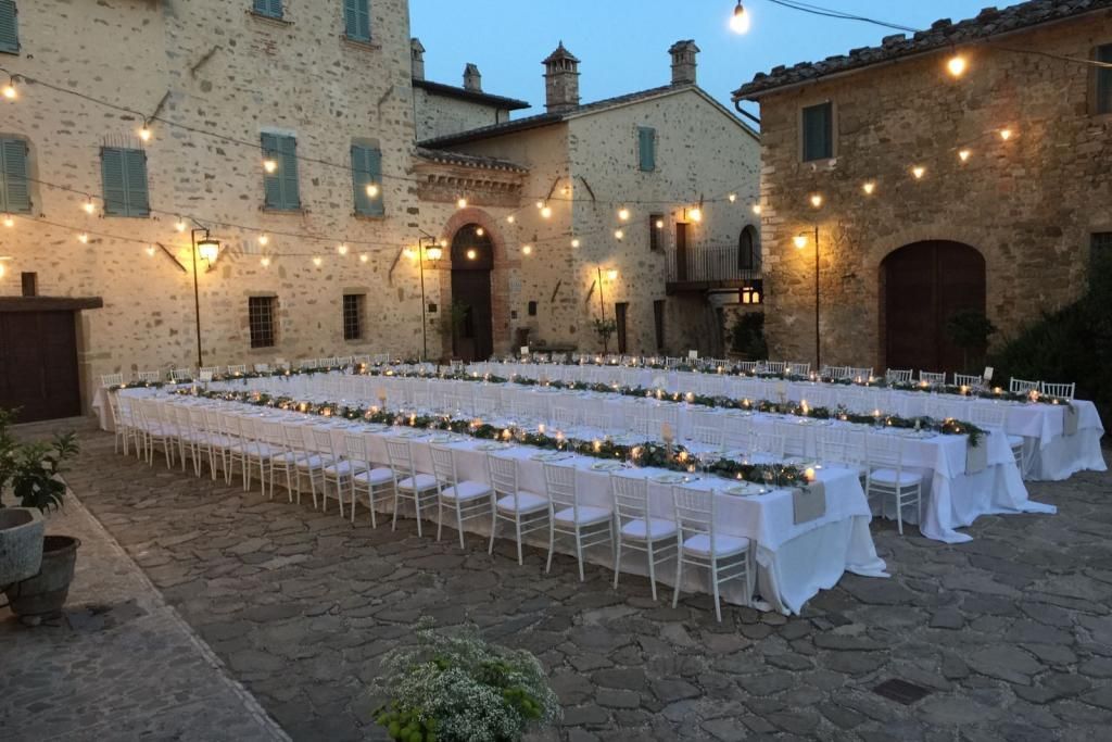 Ci sono molti tavoli e sedie al centro del cortile.