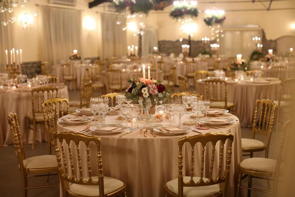 Una grande sala piena di tavoli e sedie allestita per un ricevimento di matrimonio.