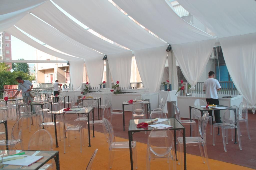 Una grande stanza con tavoli e sedie sotto una tenda.