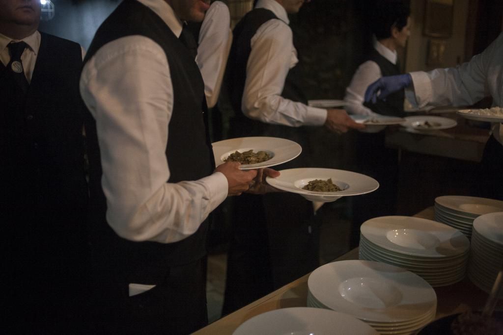 Un gruppo di uomini è in piedi attorno a un tavolo con piatti pieni di cibo