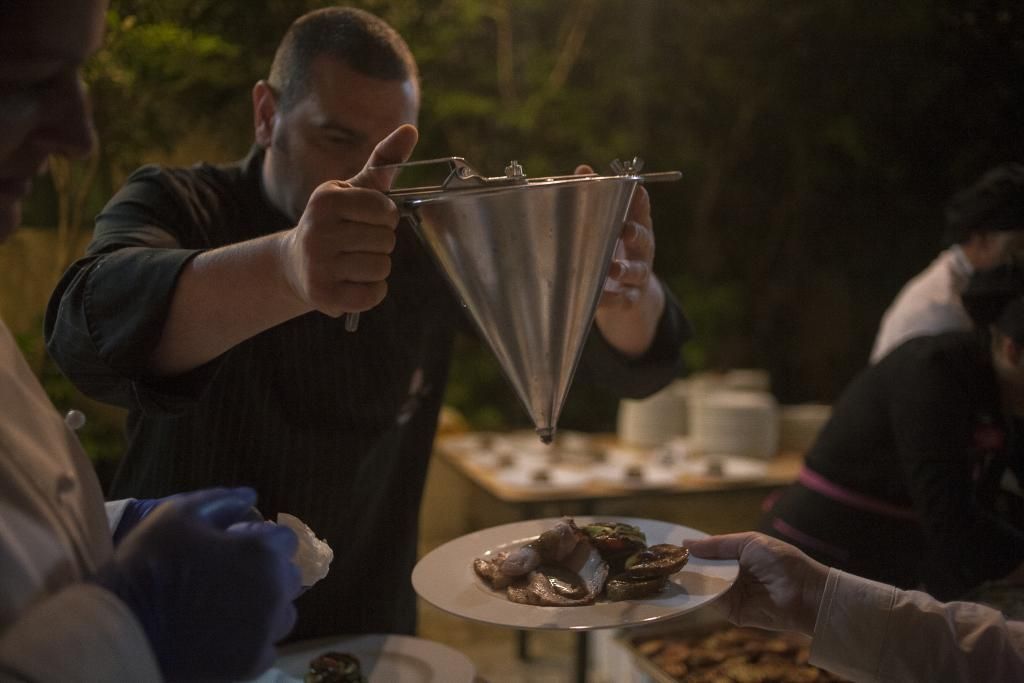 Un uomo versa del liquido in un piatto pieno di cibo.