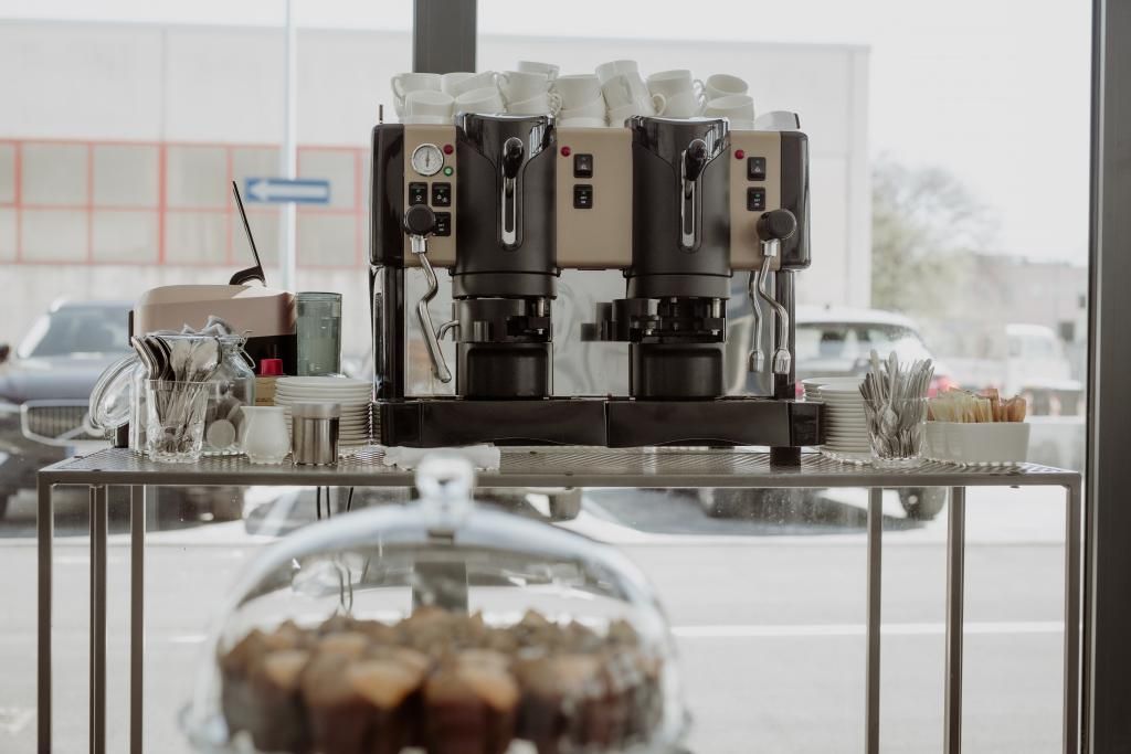 Una macchina per il caffè è posata su un tavolo davanti a una finestra.