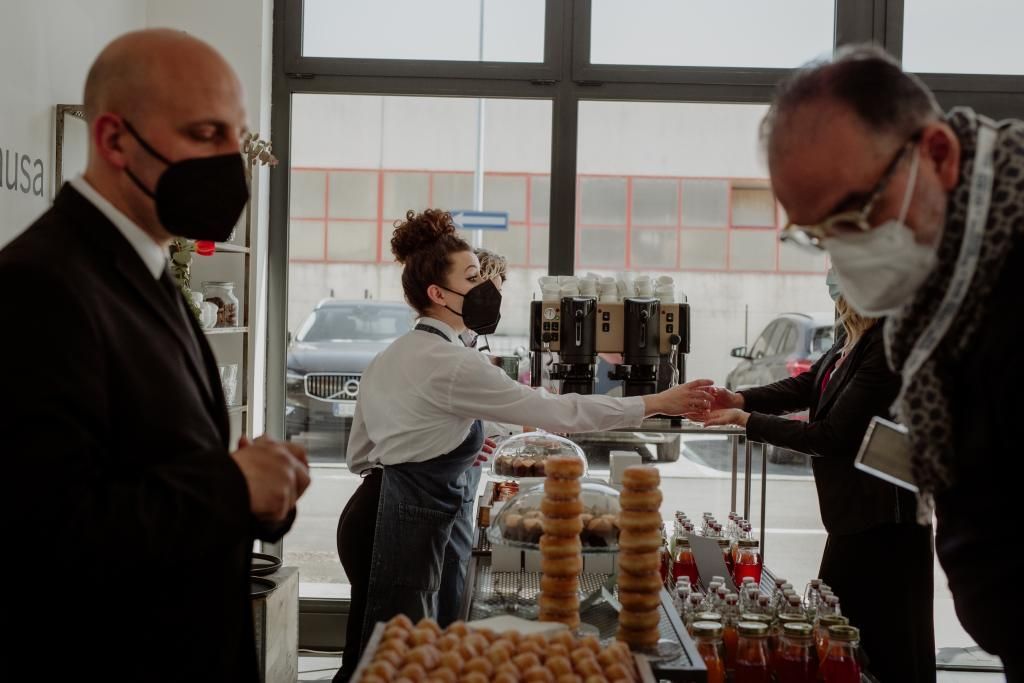 Un gruppo di persone che indossano maschere per il viso sono in piedi attorno a un tavolo in un ristorante.