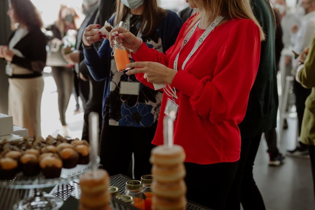 Un gruppo di persone è in piedi attorno a un tavolo con cibo e bevande.