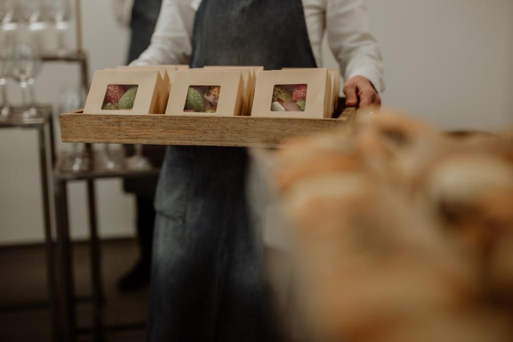 Una persona tiene in mano un vassoio di legno con sopra scatole di cibo.