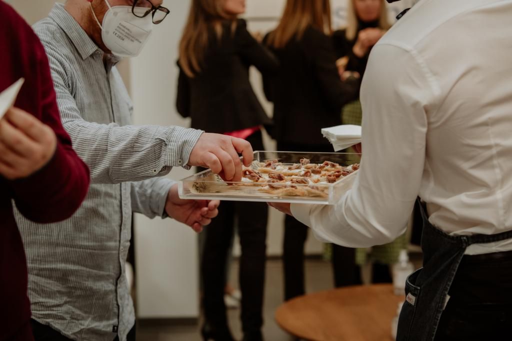 Un uomo che indossa una maschera serve cibo a un gruppo di persone.