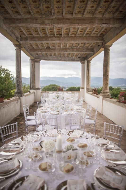 Una lunga tavola apparecchiata per un ricevimento di nozze con vista sulle montagne.