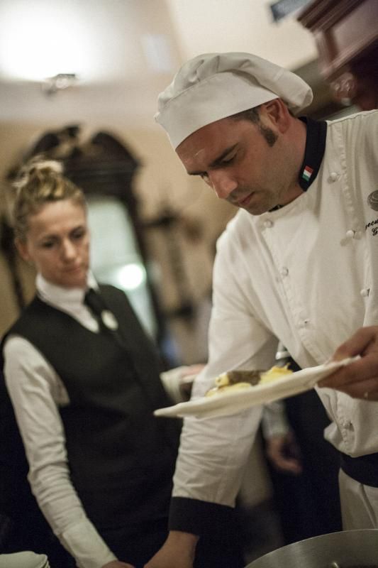 Un uomo con un cappello da chef tiene in mano un piatto di cibo