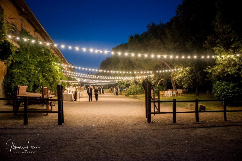Una fila di lucine sospese su una strada sterrata di notte.