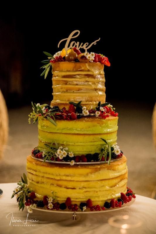 Su un tavolo è seduta una torta nuziale fatta di frittelle e frutti di bosco.