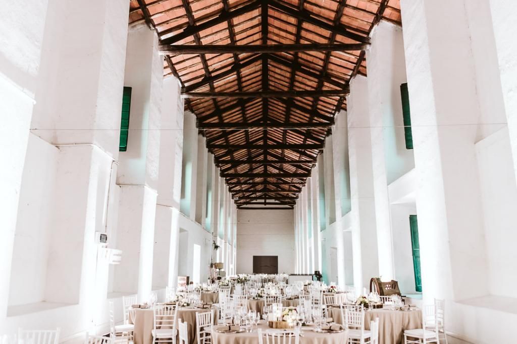 Una lunga sala con tavoli e sedie allestita per un ricevimento di nozze.