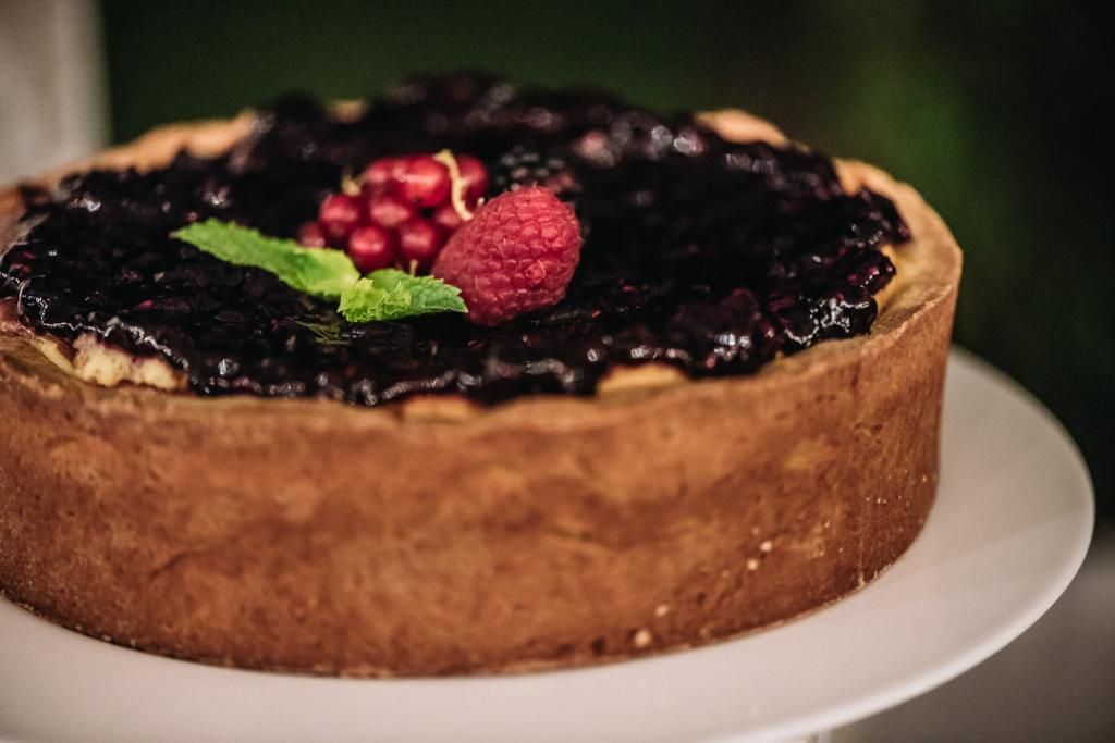 Una cheesecake con frutti di bosco in cima è su un piatto bianco.