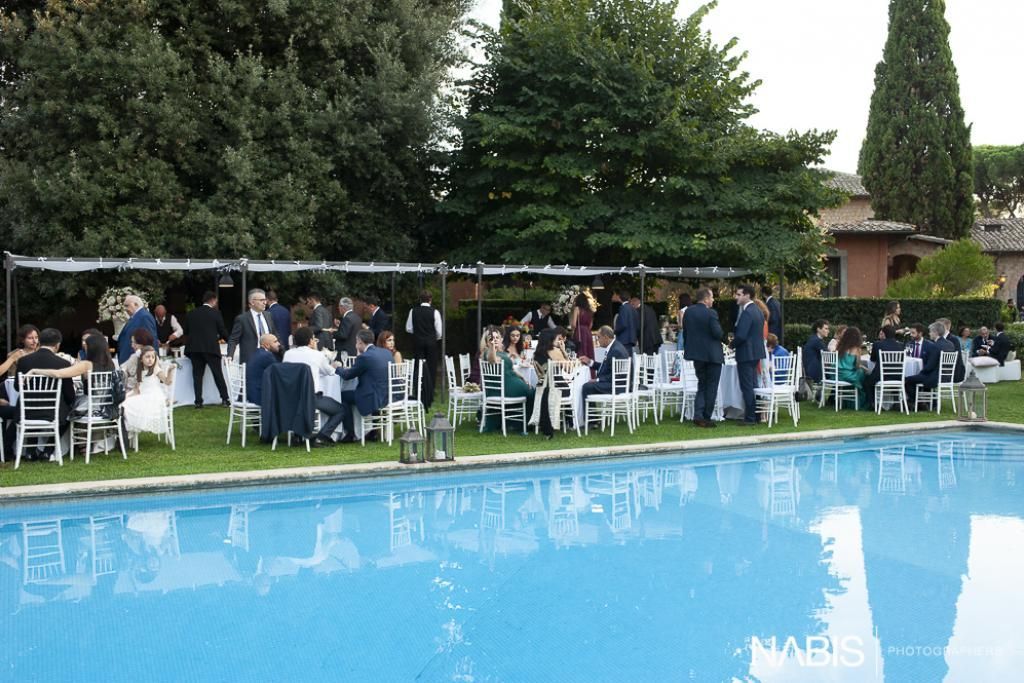 Un gruppo di persone sedute ai tavoli vicino a una piscina