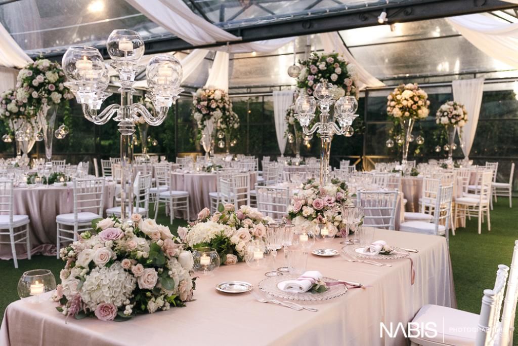 Sotto una tenda c'è un grande tavolo con dei fiori sopra.