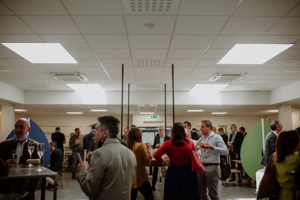 Un gruppo di persone è in piedi attorno ai tavoli in una stanza.