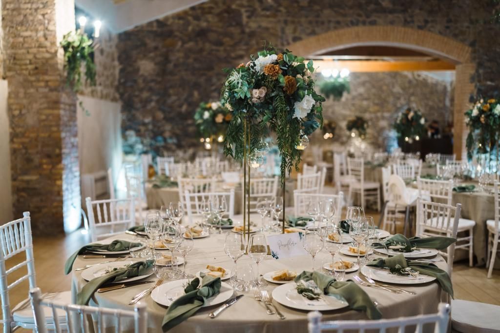 Un'ampia sala con tavoli e sedie allestita per un ricevimento di matrimonio.