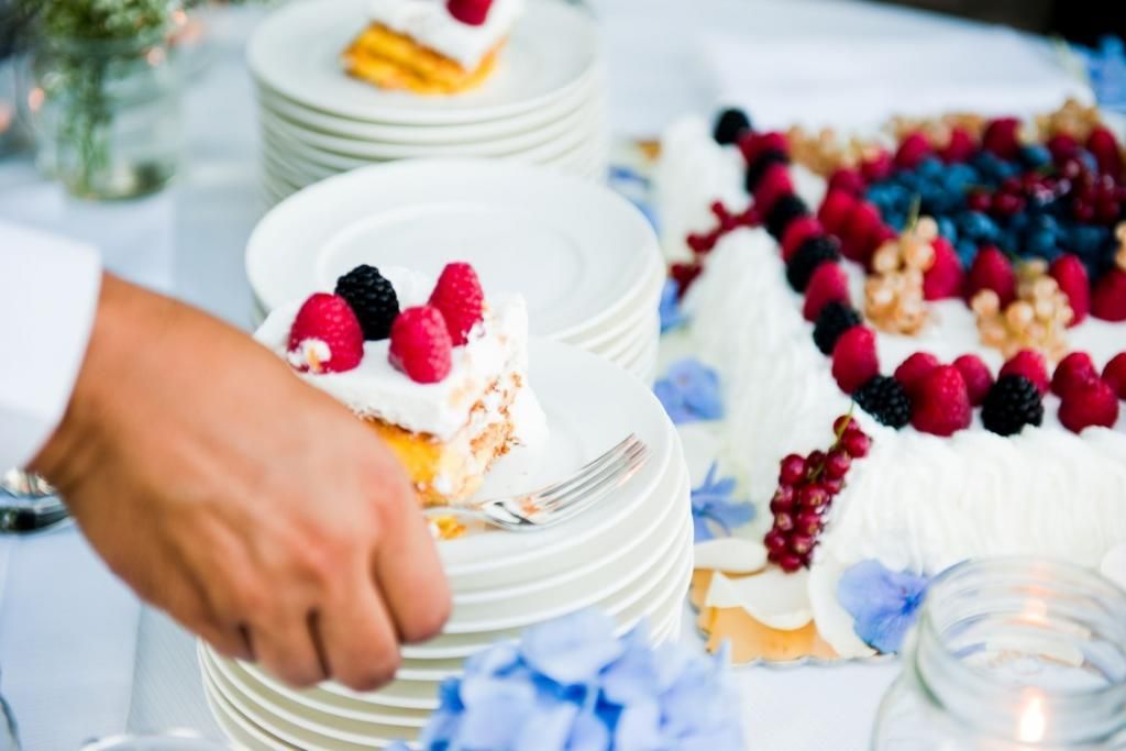 Una persona sta tagliando una fetta di torta su un piatto.