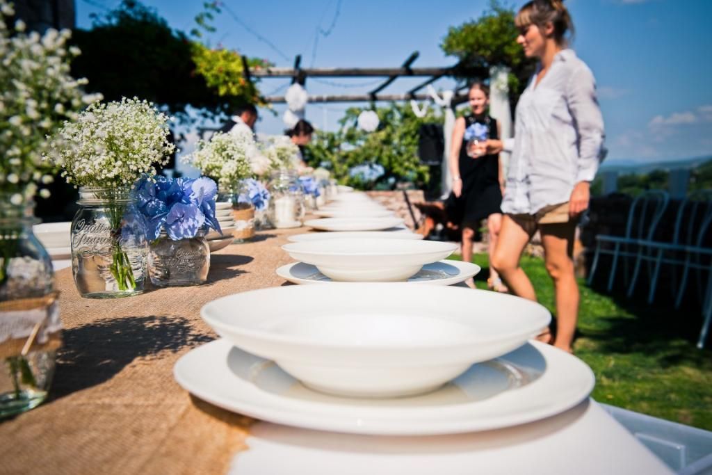 Una donna è in piedi accanto a un lungo tavolo su cui sono appoggiati piatti e ciotole.