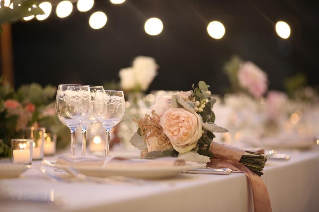 Una tavola apparecchiata per un ricevimento di nozze con sopra un mazzo di fiori.